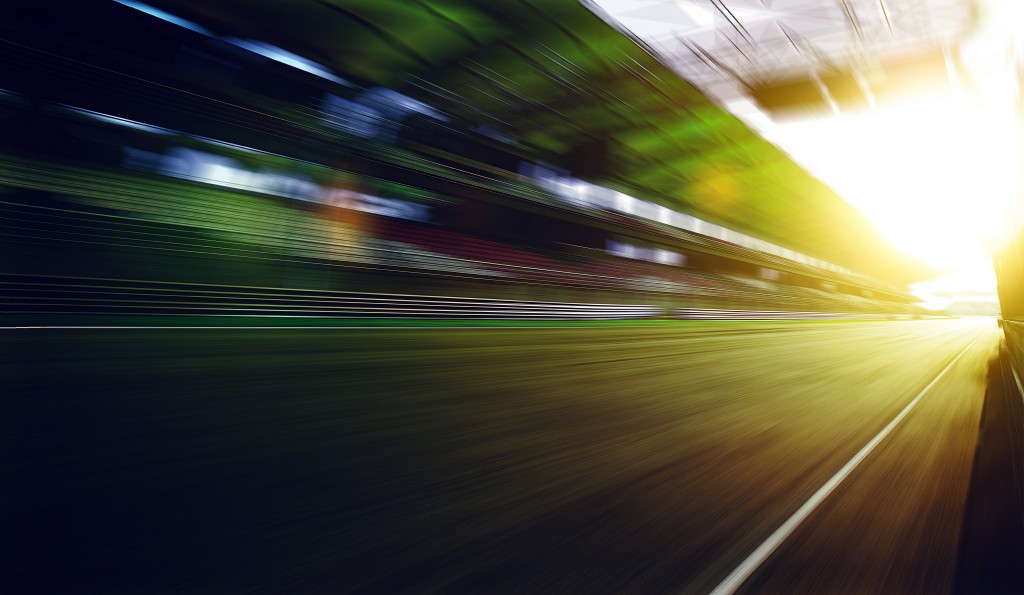 Foward motion speed lens blur racing circuit background with seated stand , sunset scene .